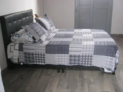 a bed with a checkered blanket and pillows at ANGIE`s HOUSE in Manizales