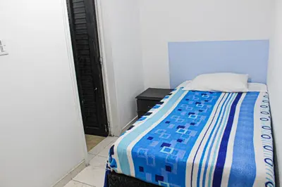 a bedroom with a bed with a blue and white comforter at El Cable Hostal in Manizales