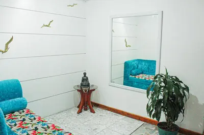 a living room with a blue chair and a mirror at El Cable Hostal in Manizales