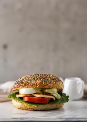a bagel sandwich with lettuce tomato and cheese on a table at Soul Lifestyle Hotel in Medellín