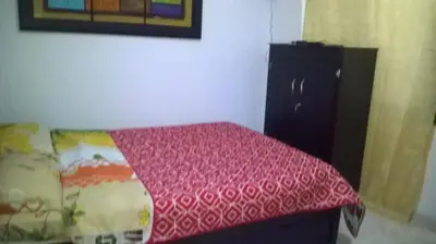 a bedroom with a bed and a black refrigerator at Apartaestudios El Cable in Manizales
