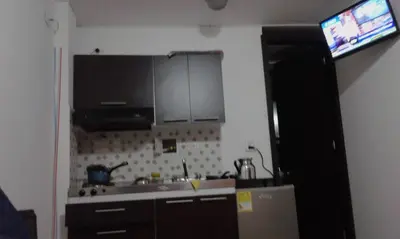 a kitchen with a sink and a refrigerator and a television at Apartaestudios El Cable in Manizales
