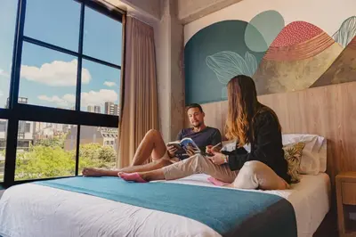 a man and a woman sitting on a bed at Los Patios Hostel Medellin in Medellín
