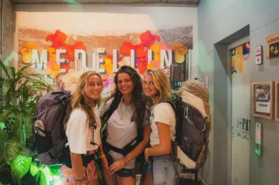 three girls with backpacks standing in a room at Los Patios Hostel Medellin in Medellín