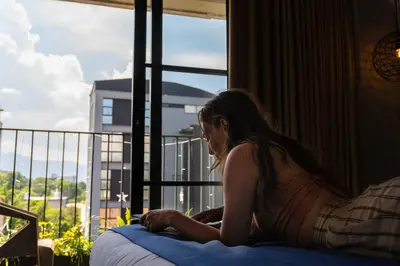 a woman sitting on a bed looking out a window at Los Patios Hostel Medellin in Medellín