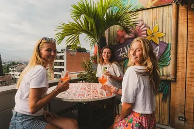 three girls sitting at a table on a balcony at Los Patios Hostel Medellin in Medellín