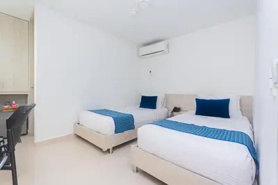 a bedroom with two beds and a desk and a table at Hotel Laureles Plaza in Medellín