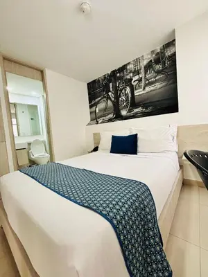 a bedroom with a large bed with a picture on the wall at Hotel Laureles Plaza in Medellín