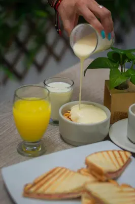 a person pouring cheese into a bowl of crackers and orange juice at Hotel Laureles Plaza in Medellín