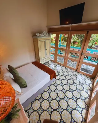a bedroom with a bed and a tv and windows at Hotel Lago Valdivia in Jardin