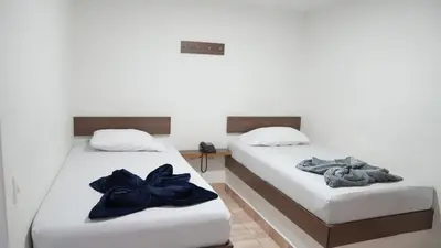 two beds in a room with white walls at Hotel Salamanca Resort in Itagüí