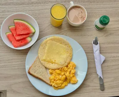 a breakfast plate with eggs and toast and a bowl of fruit at Hotel Casa 10 in Medellín