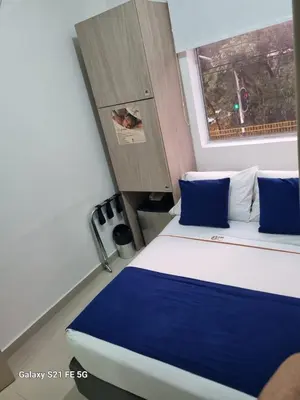 a bedroom with a bed with blue pillows and a window at Hotel Casa 10 in Medellín