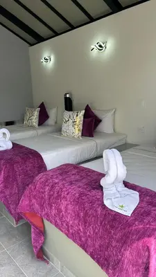 two beds in a room with purple sheets and towels at STAR CENTER Hotel Boutique in Rionegro