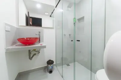 a bathroom with a glass shower and a red bowl at Living Hotel in Medellín