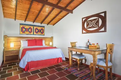 a bedroom with a bed and a table and a desk at Hotel Zocalo Campestre in Guatapé