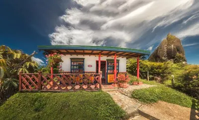a small house with a gate in front of a mountain at Hotel Zocalo Campestre in Guatapé