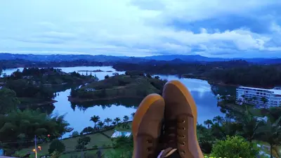 a close up of a persons shoes on a view of a river at Hotel Zocalo Campestre in Guatapé