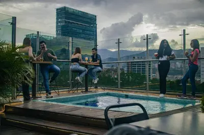 a group of people sitting at tables next to a pool at Rango Hostel Boutique in Medellín