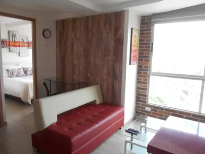 a living room with a red couch and a bedroom at All Inclusive Suites in Medellín
