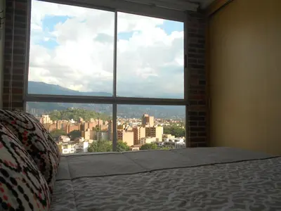 a bedroom with a large window overlooking a city at All Inclusive Suites in Medellín