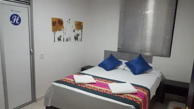 a bedroom with a large bed with blue pillows at Hotel La Castellana in Manizales