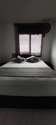a bed with two pillows in a bedroom with a window at Hotel La Castellana in Manizales