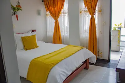 a bedroom with a large bed with an orange blanket at Hotel Royal Suite in Manizales
