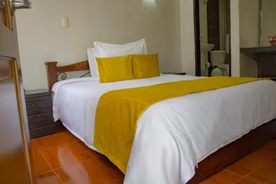 a bedroom with a large bed with a yellow blanket at Hotel Royal Suite in Manizales