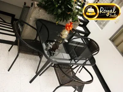 a glass table and chairs with a vase on it at Hotel Royal Suite in Manizales