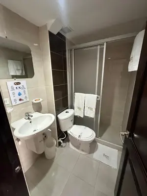 a bathroom with a toilet and a sink and a shower at Hotel Royal Suite in Manizales