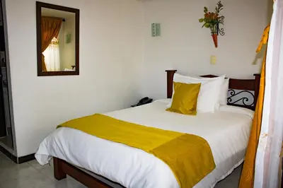 a bedroom with a large bed with a yellow blanket at Hotel Royal Suite in Manizales