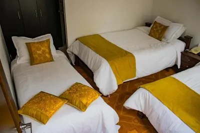 a room with three beds with yellow pillows at Hotel Royal Suite in Manizales