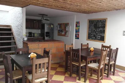 a dining room with tables and chairs and a kitchen at Sergeant Pepper's Hostel in Jardin