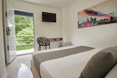 a bedroom with a bed and a television and a window at Arena de Santa Fe by Bernalo Hotels in Santa Fe de Antioquia