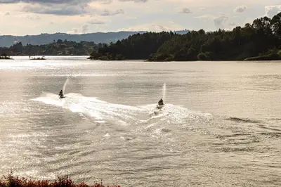 two people are water skiing on a lake at Hotel La Magdalena in Guatapé