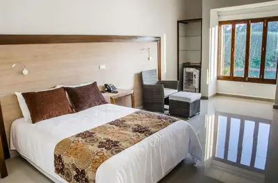 a bedroom with a bed and a desk and a chair at Hotel La Magdalena in Guatapé