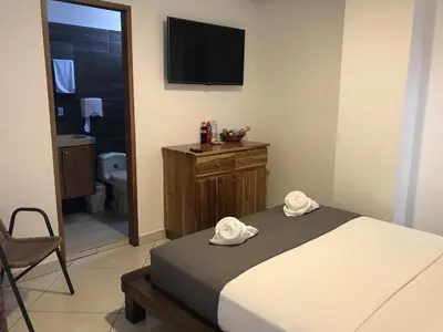 a bedroom with a bed and a tv on the wall at Hotel Bahia Guatape in Guatapé