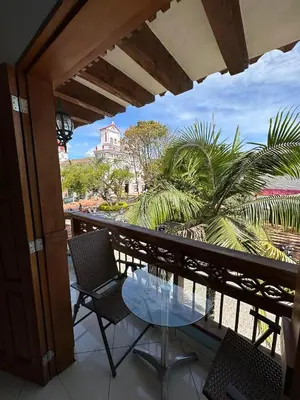 a balcony with a table and chairs and palm trees at Hotel Bahia Guatape in Guatapé