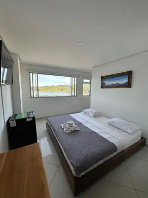 a bedroom with a large bed and a window at Hotel Bahia Guatape in Guatapé