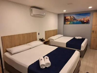 a hotel room with two beds and a tv at Hotel Suramericana in Medellín