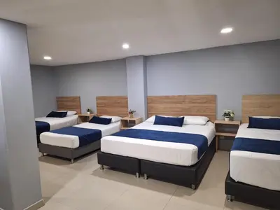 a room with three beds with blue and white sheets at Hotel Suramericana in Medellín