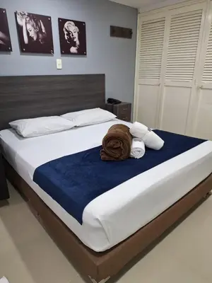 a large bed with two towels on it at Hotel Suramericana in Medellín