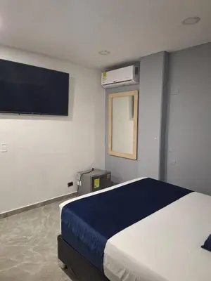 a bedroom with a bed and a flat screen tv at Hotel Suramericana in Medellín