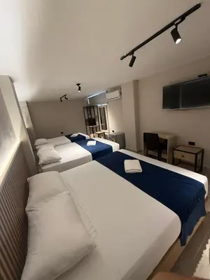a room with four beds with blue and white sheets at Hotel Suramericana in Medellín