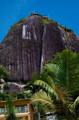 a mountain with palm trees in front of a building at Mansión by Bernalo Hotels in Guatapé