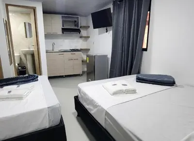 two beds in a small room with a kitchen at hotel medellin calasanz in Medellín