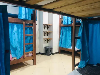 a room with two bunk beds with blue curtains at Lake View Hostel in Guatapé