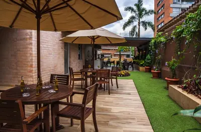 an outdoor patio with tables and chairs with umbrellas at Hotel Lomas 10 Medellin in Medellín