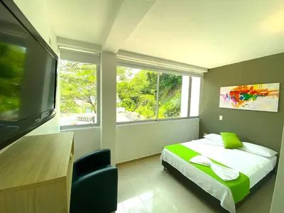 a bedroom with a bed and a large window at Biohotel Rio Claro in Doradal
